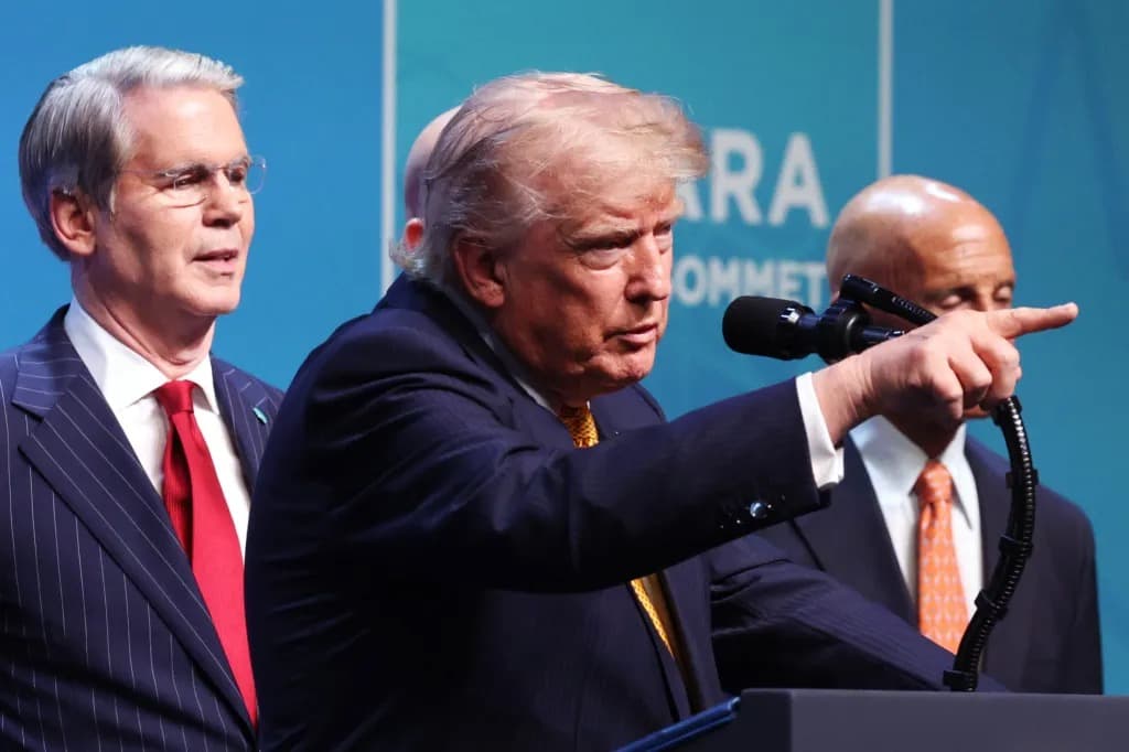 President Trump gesturing and pointing while speaking at a podium flanked by two officials